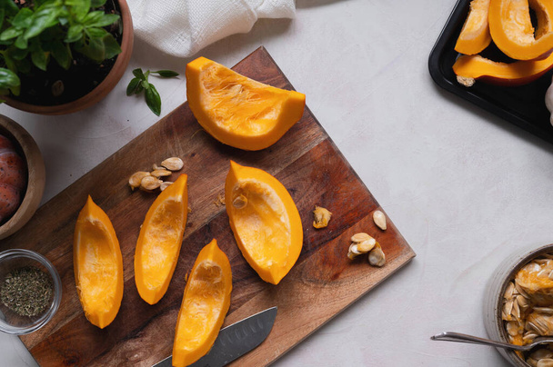Vista superior de rodajas frescas de calabaza naranja en la tabla de cortar. Cocinar ingredientes para una sopa de mantequilla, pastel o comida de otoño - Foto, imagen