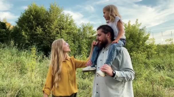 una familia joven se comunica en un paseo por la naturaleza y mira a la izquierda - Metraje, vídeo