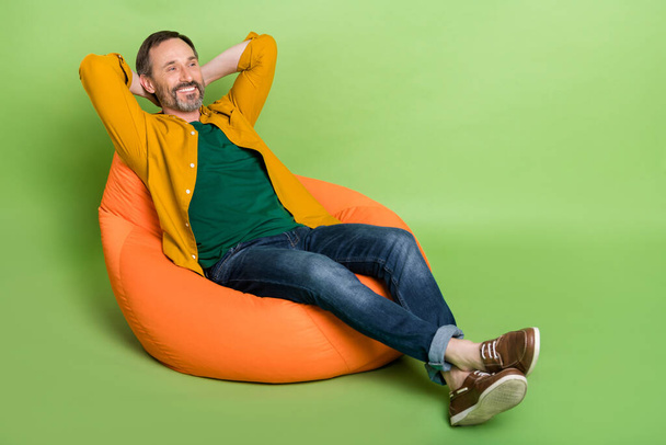 Full size profile side photo of mature man happy positive smile rest chair bean hands behind head isolated over green color background - Valokuva, kuva