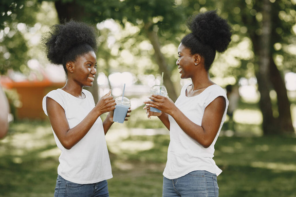 Twin sisters holding a cups with drinks and looking on each other - Foto, immagini