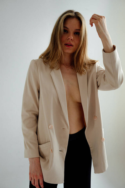 kaunis tyttö mustat housut ja kevyt takki poseeraa valkoinen studio tausta  - Valokuva, kuva