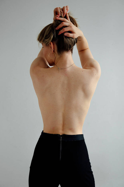 back view of naked beautiful girl in black pants posing on white studio background  - Фото, зображення