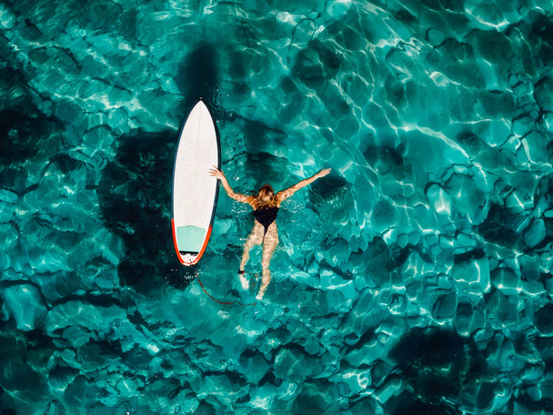 Серферна дівчина плаває з дошкою для серфінгу в прозорому бірюзовому океані. Вид зверху повітря
 - Фото, зображення