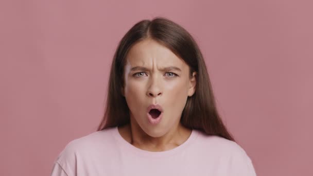 Σοκαρισμένη γυναίκα που εκφράζει αηδιαστικό αρνητικό συναίσθημα κουνώντας το κεφάλι, ροζ φόντο - Πλάνα, βίντεο