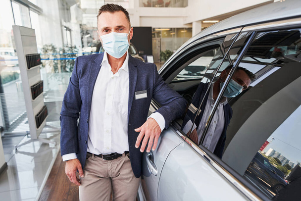 Autószalon alkalmazott visel orvosi maszkot a munkahelyen - Fotó, kép