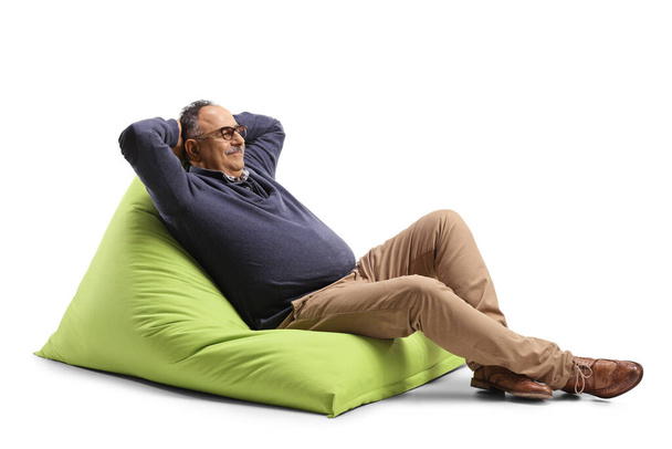 Mature man sitting on a green bean bag chair and relaxing isolated on white background - Фото, зображення