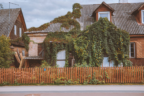 Spokojny krajobraz tradycyjnego wiejskiego domu porośniętego roślinami za drewnianym płotem - Zdjęcie, obraz