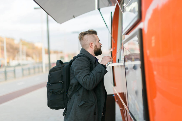 Portrait of man choosing fast food in food truck in the street. Meal, food industry and streetfood concept. - Photo, Image