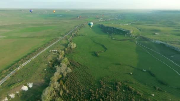 Draufsicht auf das Ballonfestival. Schuss. Wunderschönes Panorama mit Luftballons vor dem Hintergrund grüner Felder und Horizonte. Landschaft mit Luftballons und Horizont an sonnigen Tagen - Filmmaterial, Video