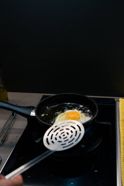person fries an egg at home - Фото, изображение