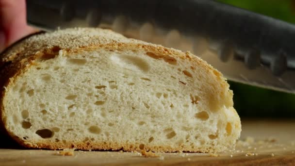 Primo piano di mano con coltello da cucina affettare pane croccante al chiuso - Filmati, video