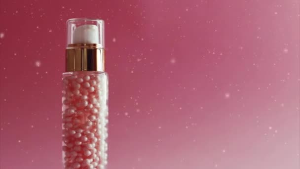 Producto para el cuidado de la piel en botella dorada sobre fondo rosa - Metraje, vídeo