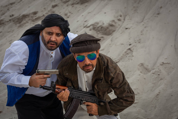 Os Talibãs estão a planear ataques terroristas com armas. Soldado árabe em uma cobertura para a cabeça feita do keffiyeh nacional com armas em suas mãos. - Foto, Imagem