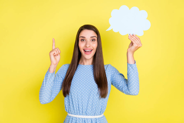 Photo of sweet impressed woman dressed blue clothes holding mind cloud pointing finger empty space isolated yellow color background - Фото, изображение