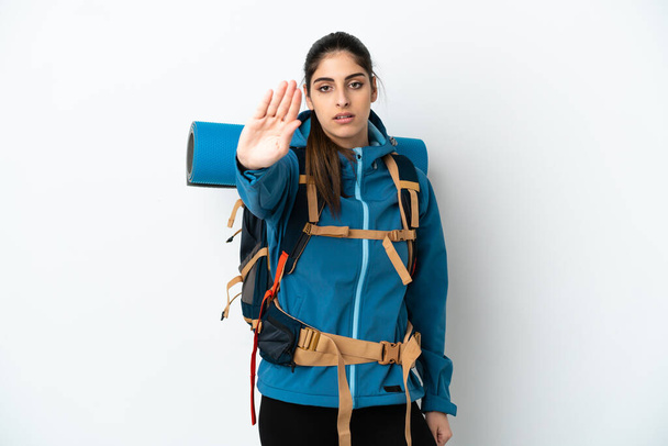 Giovane alpinista uomo con un grande zaino su sfondo isolato facendo gesto di stop - Foto, immagini