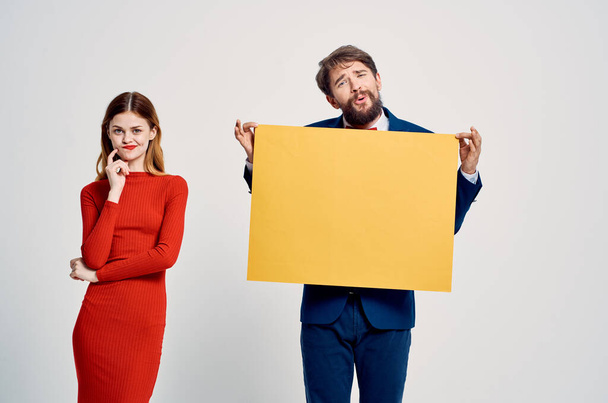 a man in a suit next to a woman in a red dress yellow mockup poster advertising - Foto, afbeelding