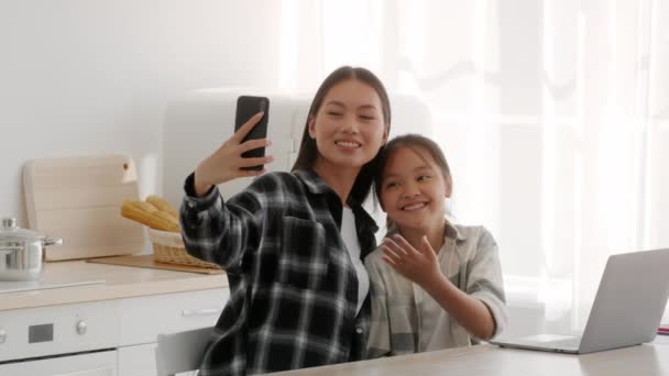 Cinese madre e figlia making selfie su telefono in cucina - Filmati, video