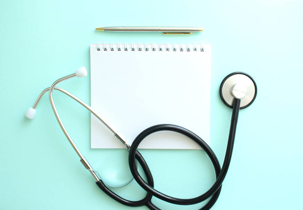 White notepad with the place and a stethoscope on a blue background. Medical concept - Fotó, kép
