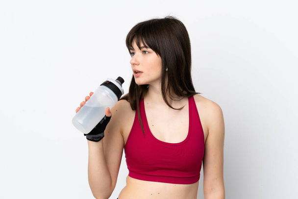 Νεαρή αθλητική γυναίκα απομονωμένη σε λευκό φόντο με αθλητικό μπουκάλι νερού - Φωτογραφία, εικόνα