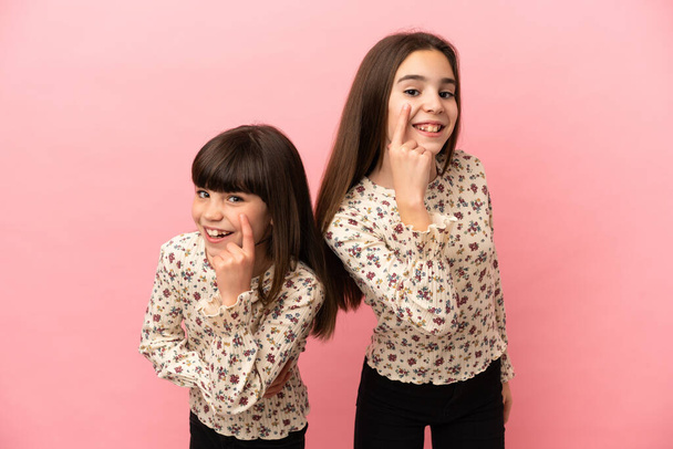 Hermanitas niñas aisladas sobre fondo rosa mirando hacia el frente - Foto, imagen