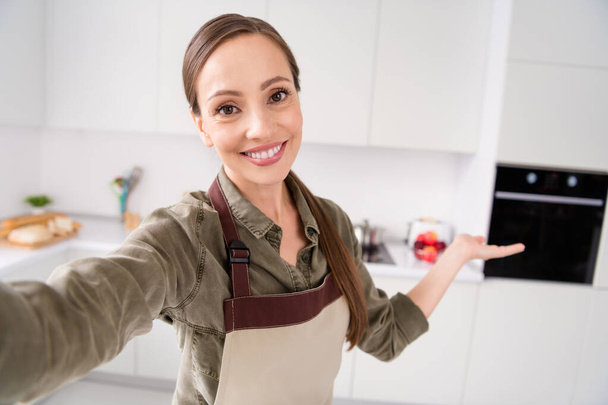 Photo of charming cute housewife dressed brown apron tacking selfie inviting you coming smiling indoors house room home - Valokuva, kuva