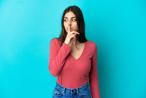 Young caucasian woman isolated on blue background showing a sign of silence gesture putting finger in mouth - Фото, зображення