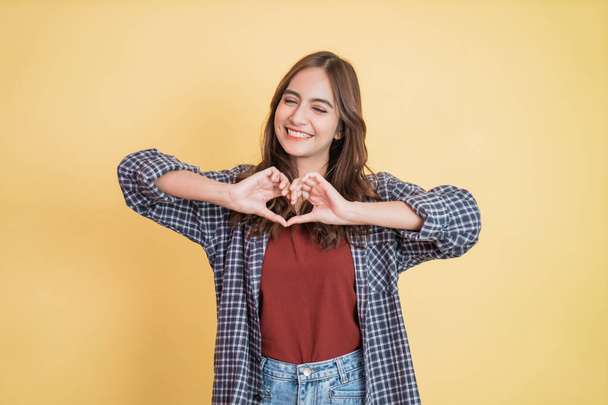 Cheerful young beautiful girl is gesturing a heart with fingers - Photo, image