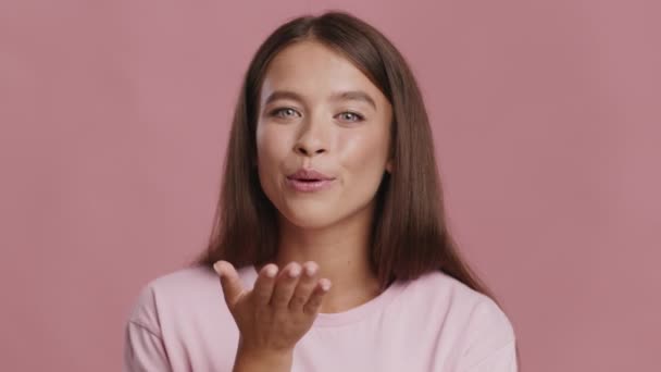 Hravé žena flirtování foukání polibek hrát s vlasy, růžové pozadí - Záběry, video