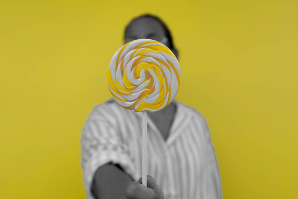Žena s sladkou lízátko na žlutém pozadí - Fotografie, Obrázek