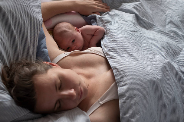 Ребенок спит вместе с матерью в постели. - Фото, изображение