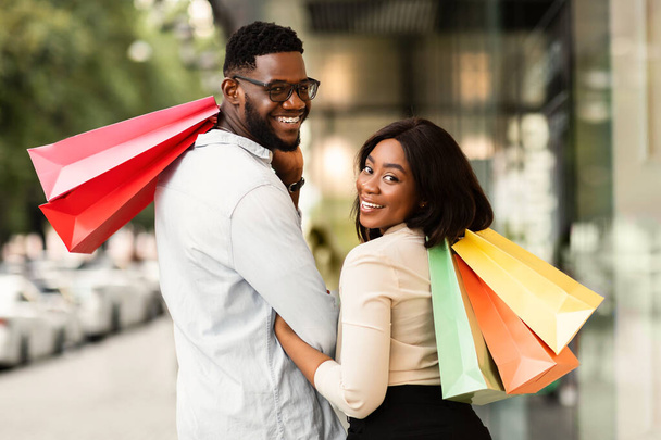Retrato de casal negro feliz olhando para trás com sacos de compras - Foto, Imagem