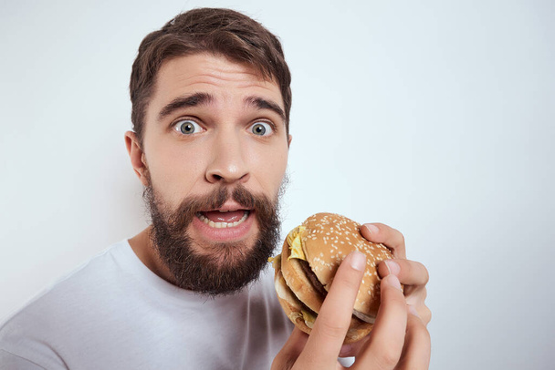 Beyaz tişörtlü bir adam bir bardak birayla fast food bar alkollü arka planda kalmış. - Fotoğraf, Görsel