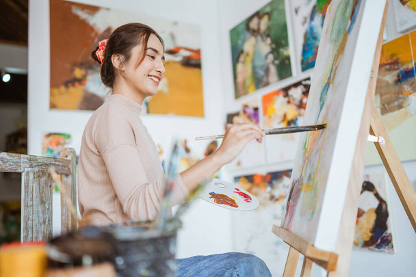 азіатська жінка живопис на полотні в її майстерні
 - Фото, зображення