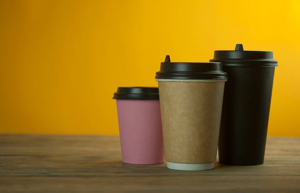 three colorful paper coffee cup on a table in a cafe, mock up - Foto, imagen