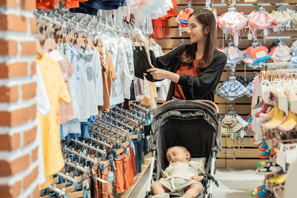 indonesian mother shopping clothes for her son in the baby boutique store - Foto, Imagem