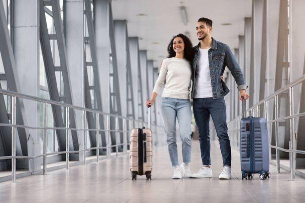 Ταξίδι διακοπών. Αραβικό ζευγάρι στέκεται με αποσκευές στο αεροδρόμιο, περιμένοντας την πτήση - Φωτογραφία, εικόνα