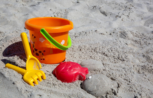 Colorful plastic toys in the sand of a beach - Photo, Image