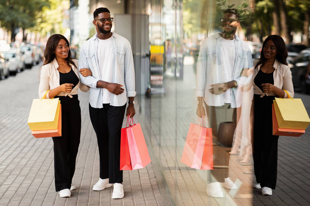 Güzel siyah bir çift alışveriş torbalarıyla yürüyor. - Fotoğraf, Görsel