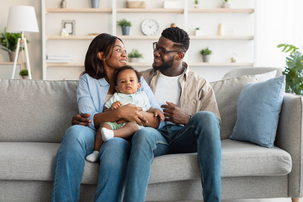 Porträt einer glücklichen schwarzen Familie, die einander lächelnd ansieht - Foto, Bild