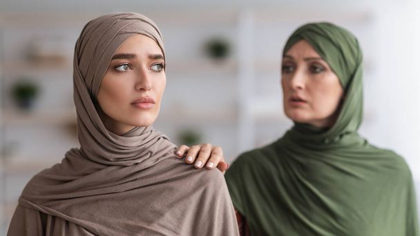 Senior Muslim Mother Touching Shoulder Of Unhappy Adult Daughter Indoor - Zdjęcie, obraz