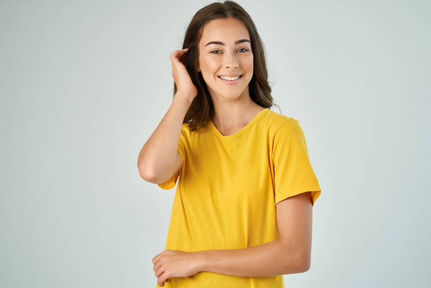 vrolijk vrouw in geel t-shirt mode kapsel glimlach studio licht achtergrond - Foto, afbeelding