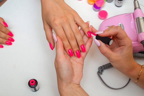 Closeup young well-groomed female hands. Manicurist doing professional manicure. Master files nails to client. - 写真・画像