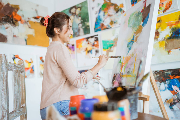 asian female painter painting on canvas in her workshop - Fotografie, Obrázek