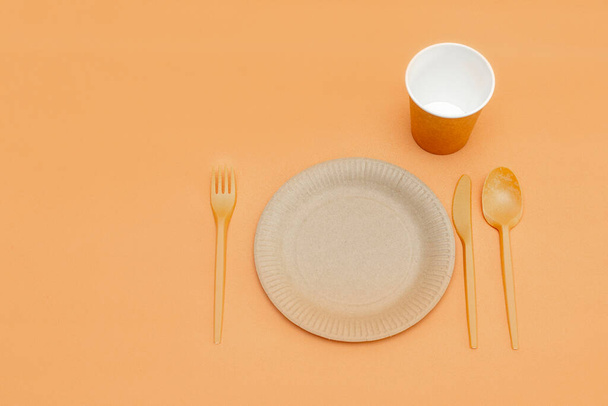 Recyclable fork, spoon, knife, plate and cup on a beige background. Kitchen utensils. Top view. Minimalist Style. Copy space. - Photo, image
