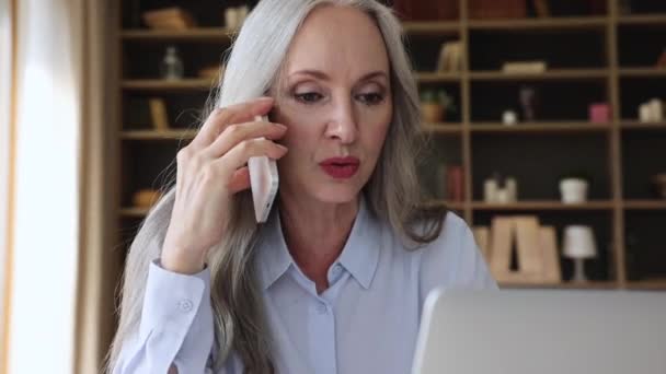 Older woman talks on phone to assistant makes order remotely - Metraje, vídeo