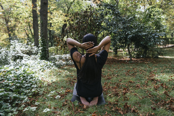 una chica haciendo yoga en la naturaleza vestida de negro - Foto, imagen