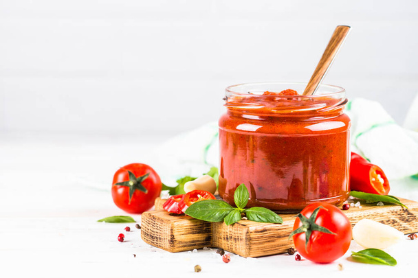 Tomatensaus met kruiden en specerijen op witte achtergrond. - Foto, afbeelding