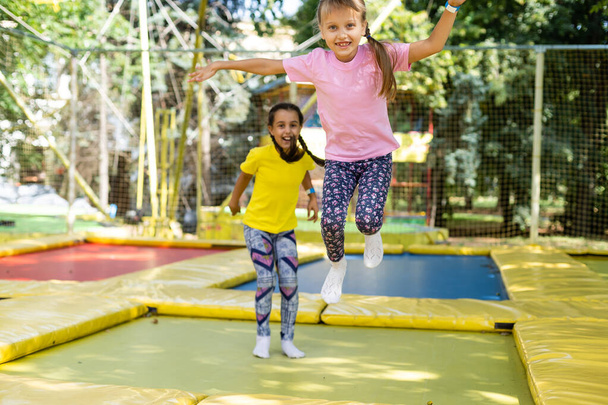 kaksi nuorta aktiivista tyttöä tekee harjoituksia kyykyssä trampoliinilla - Valokuva, kuva