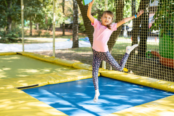 Pieni tyttö hyppää trampoliinilla kesäpäivänä. - Valokuva, kuva