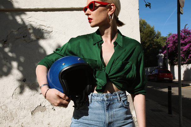 Young woman outdoor holding motorcycle helmet on street and looking away - Foto, afbeelding
